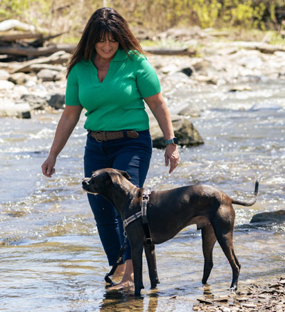 Dog trainer Lisa Yasenchak exploring a shallow creek with a black dog