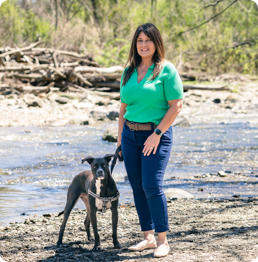 Dog trainer Lisa Yasenchak with her dog beside a creek.